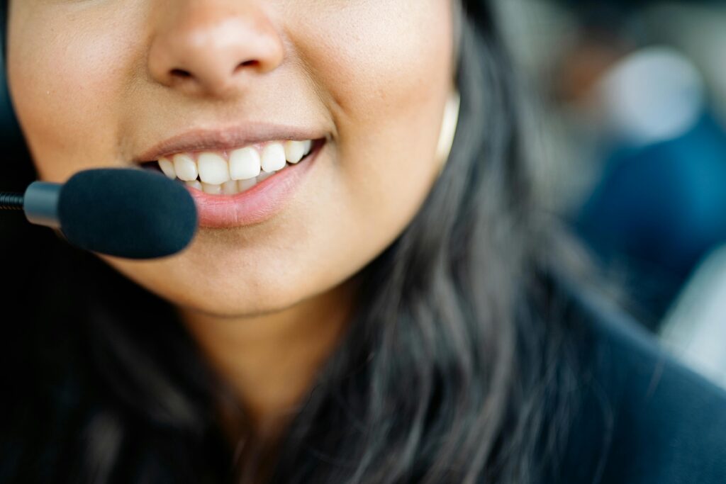 Close-up of a smiling customer service agent wearing a headset in an office environment.
